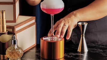A bartender preparing a cocktail with a shaker and a glass.