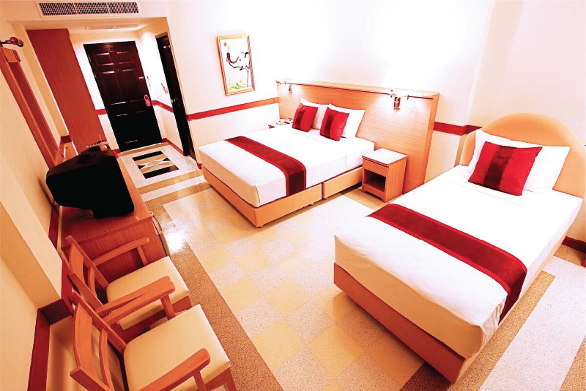 A hotel room with two beds, a desk, and a chair.