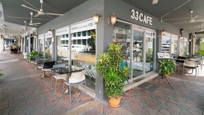 Un café avec une terrasse, des ventilateurs de plafond et une enseigne indiquant « 33CAFE ».