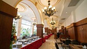 Une salle de banquet avec de longues tables recouvertes de nappes rouges, des lustres somptueux et un plafond haut orné de moulures décoratives.