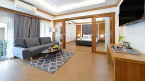 A modern hotel room with a sofa, coffee table, and a TV.