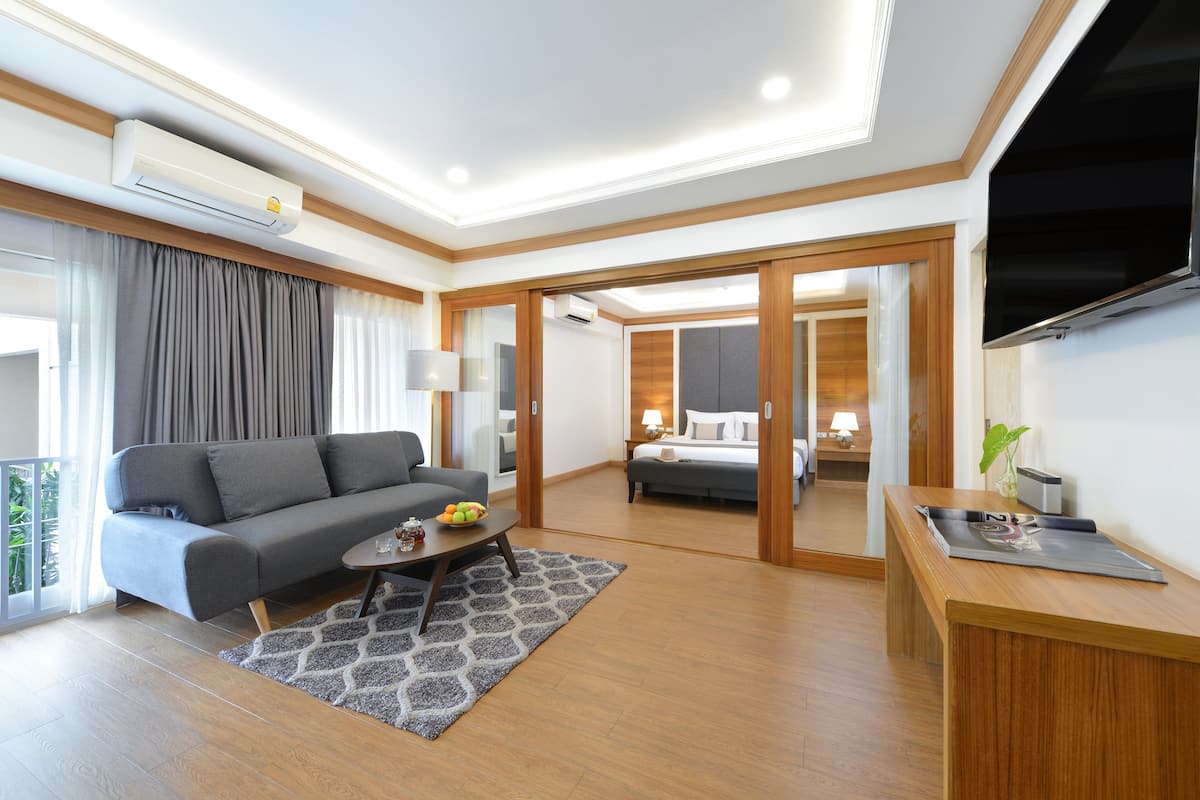 A modern hotel room with a sofa, coffee table, and a TV.