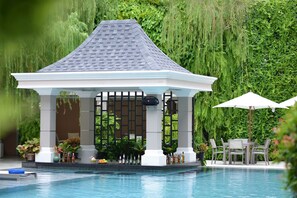 A gazebo with a tiled roof, surrounded by a pool and lush greenery. - The Beverly Hotel Pattaya (Pattaya)