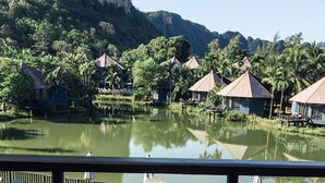 A dining table with breakfast items and a view of a lake with overwater bungalows. - Peace Laguna Resort & Spa (Krabi)