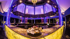 A modern interior with a central round table displaying various fruits and nuts, surrounded by seating and a unique ceiling structure with blue lighting. - Peace Laguna Resort & Spa (Krabi)
