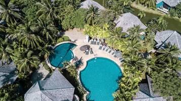 Relax by the circular swimming area surrounded by lush greenery and palm trees.