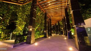 An indoor walkway with a glass enclosure on one side, surrounded by greenery and illuminated by overhead lights. - Peace Laguna Resort & Spa (Krabi)