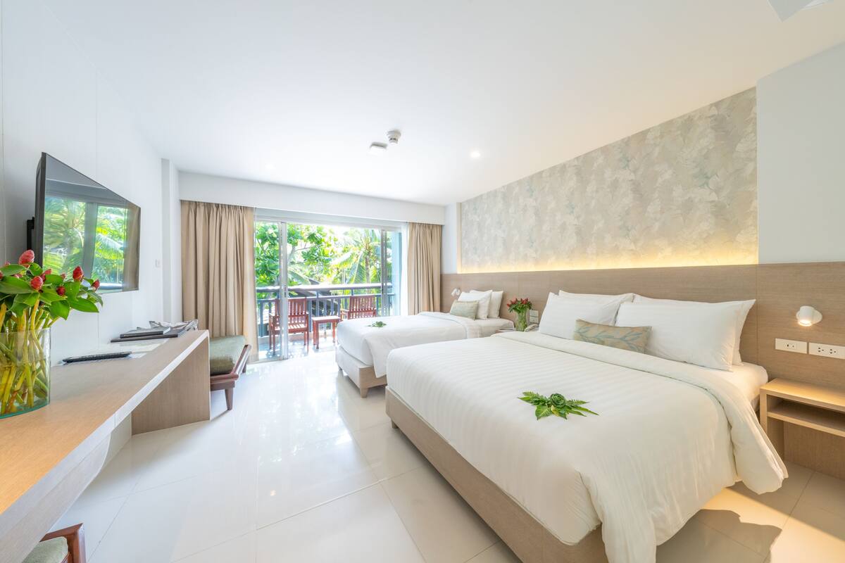 Una habitación de hotel moderna con una cama grande, un escritorio y un balcón con mobiliario exterior.