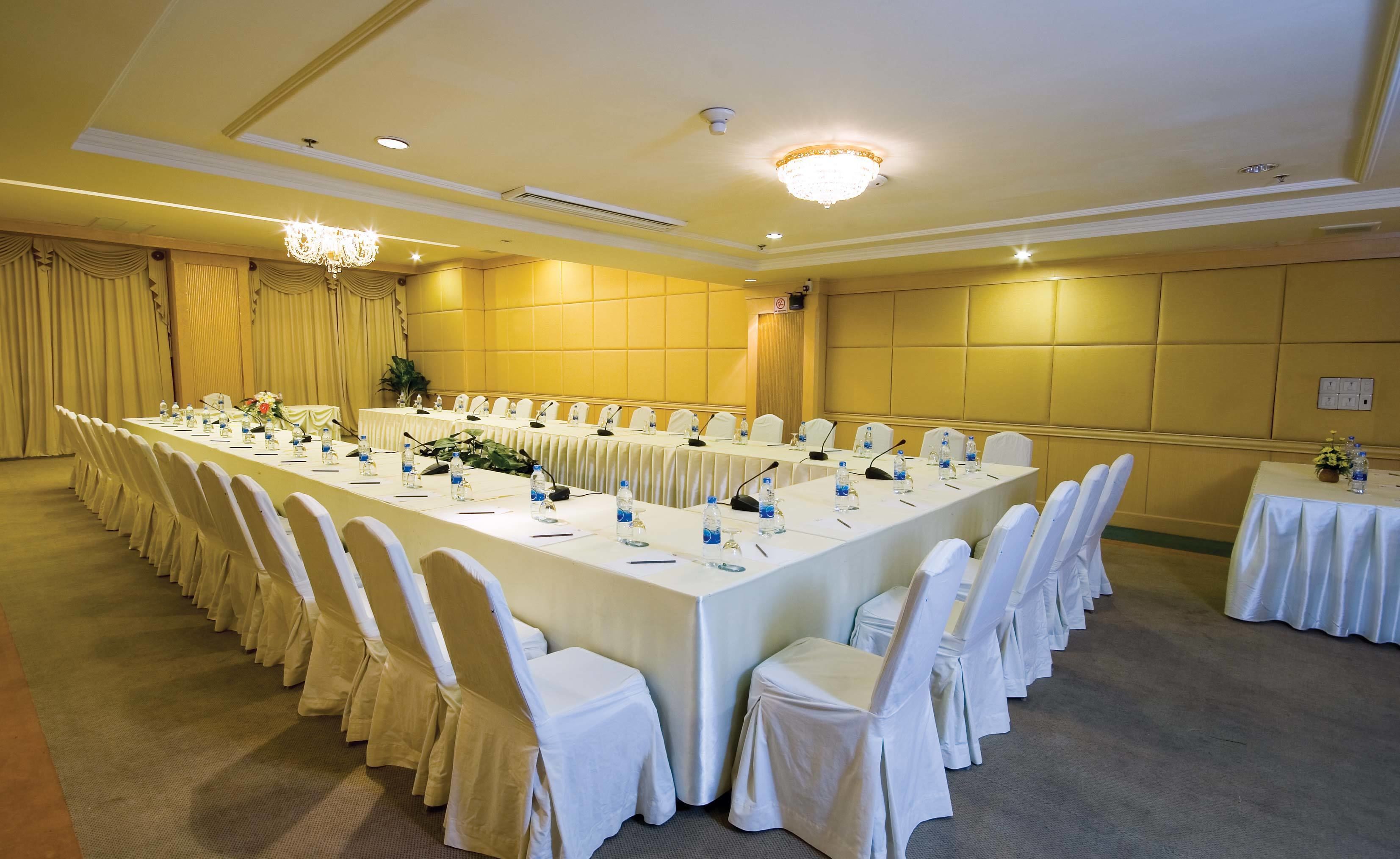 A conference room with a long table, white chairs, and microphones.