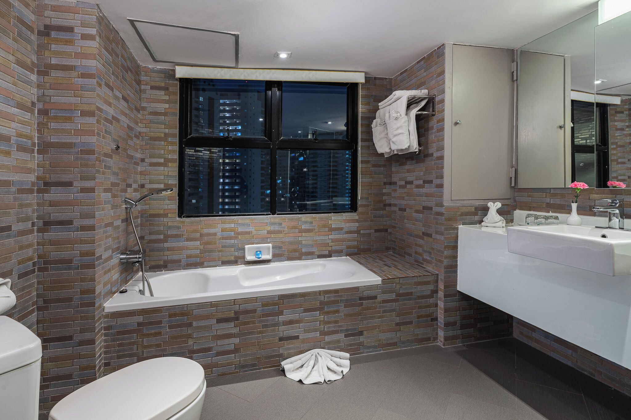 Een moderne badkamer met een bad, toilet en wastafel.
