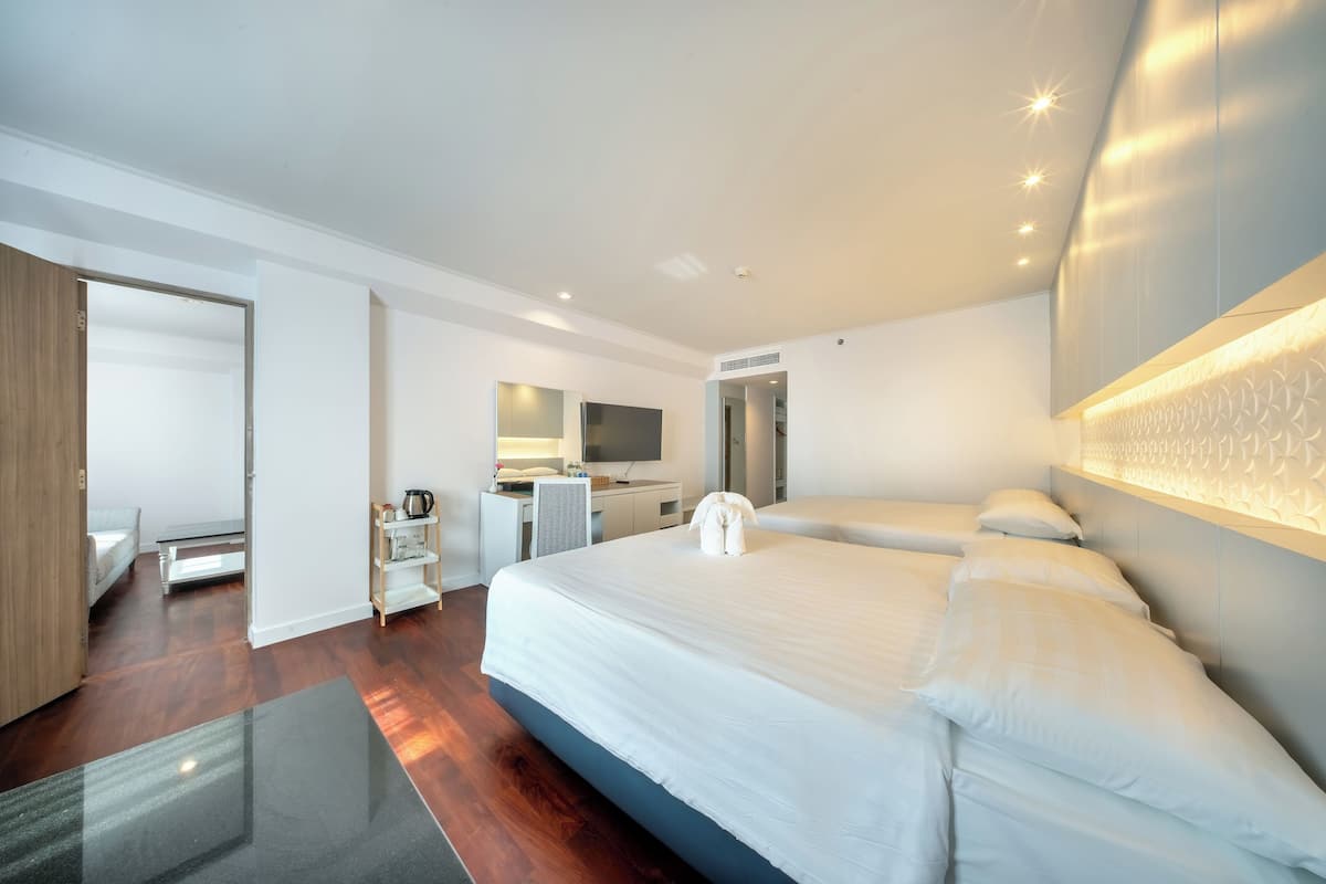 A modern hotel room with a large bed, a desk, a chair, a wardrobe, and a bathroom.