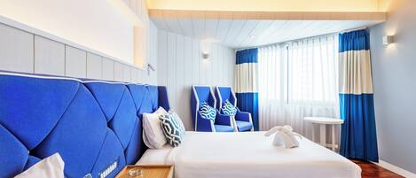 A hotel room with two beds, a wooden side table, a telephone, and a small round table.