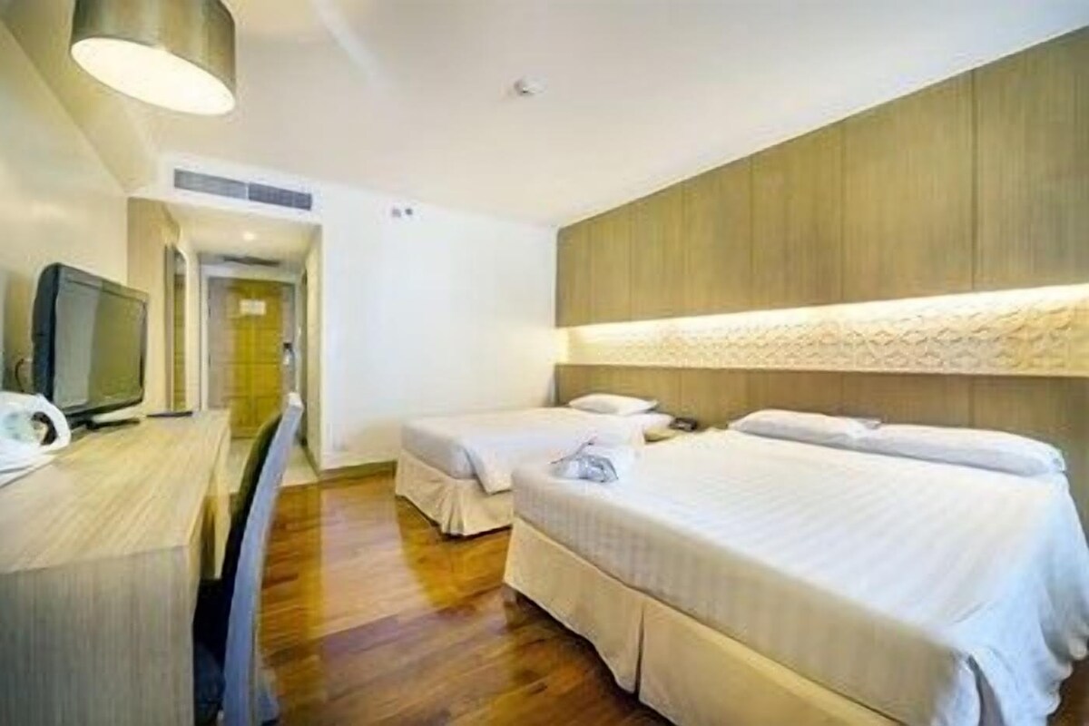 A hotel room with two beds, a desk with a computer, and a modern light fixture.