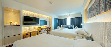 A hotel room with two beds, a desk with a flat-screen TV, a minibar, and a patterned wall.