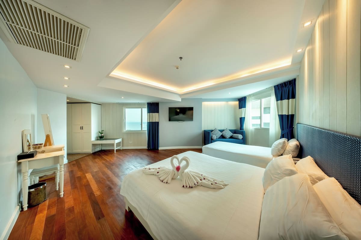 A hotel room with a large bed, a desk, a chair, and a TV on the wall.