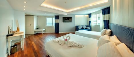 A hotel room with a large bed, a desk, a chair, and a TV on the wall.
