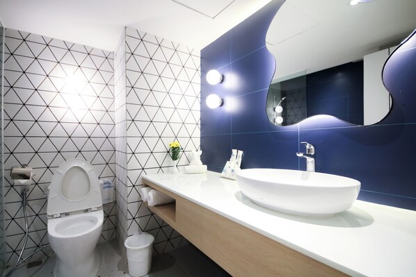 Un baño moderno con inodoro blanco, lavamanos y espejo.