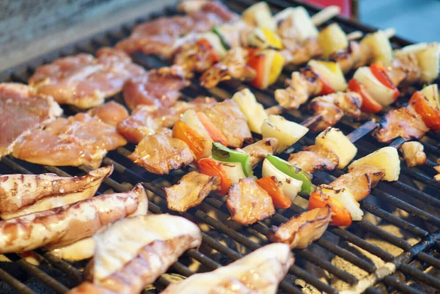 A grill with various meats and vegetables being cooked.