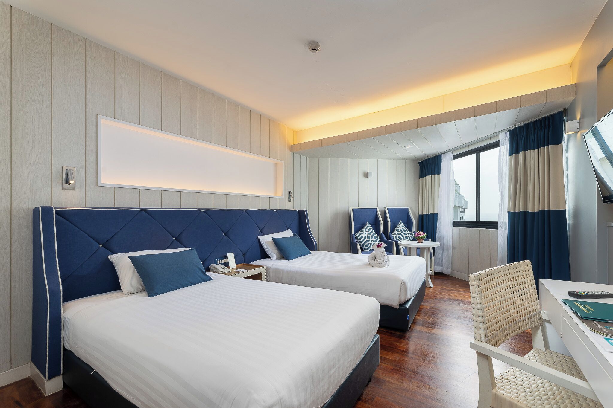 Une chambre d’hôtel avec deux lits, un bureau et une chaise.