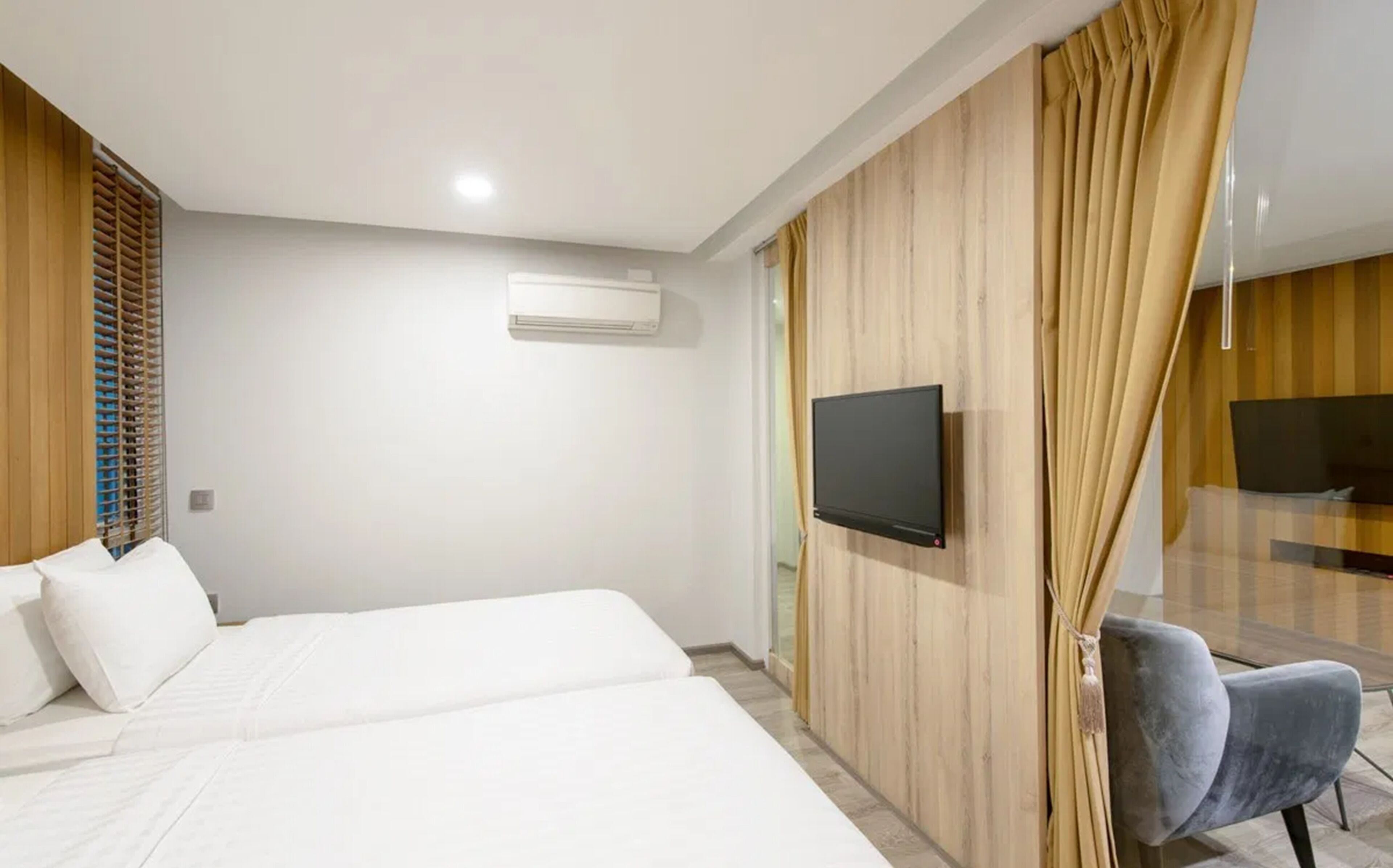 A hotel room with a bed, a TV mounted on the wall, and a chair.