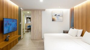 A modern hotel room with a large bed, a flat-screen TV, wooden paneling, a painting, and a view of the hallway. - The Residence Rajtaevee Hotel (Bangkok)
