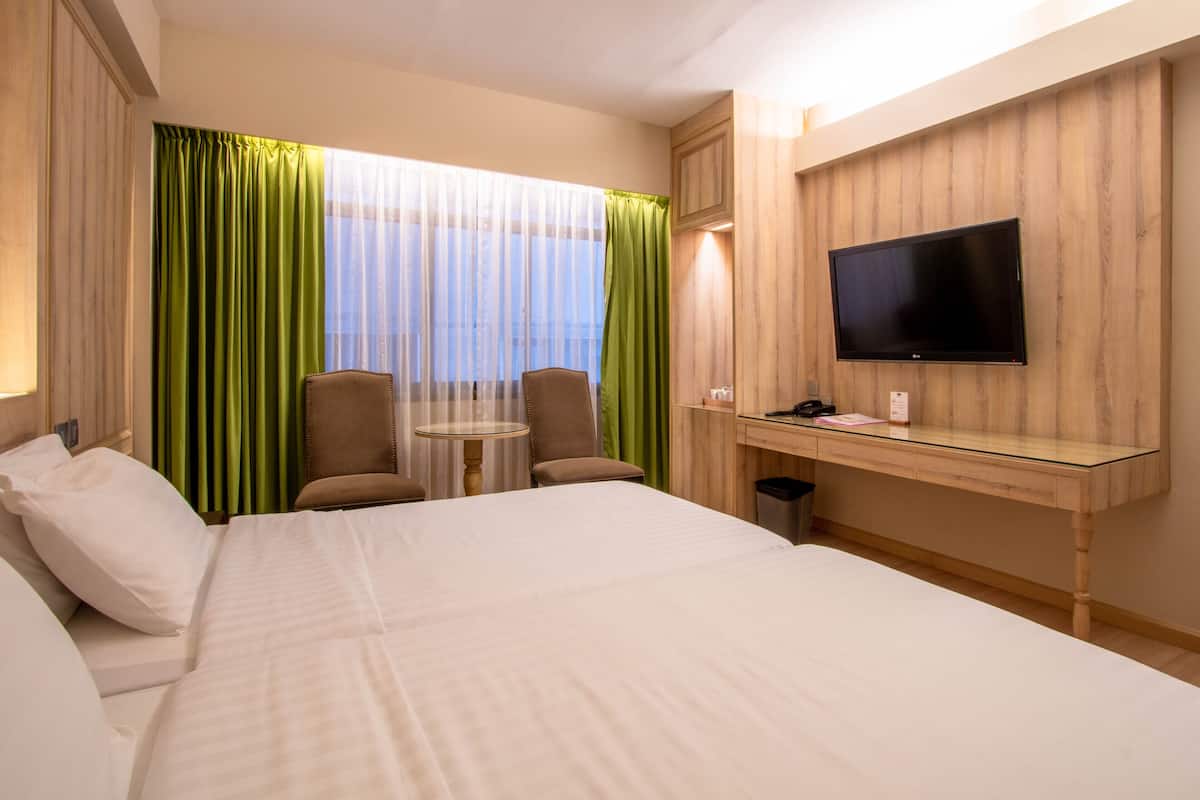 Une chambre d’hôtel avec un grand lit, un bureau avec un ordinateur, une chaise et un téléviseur fixé au mur.