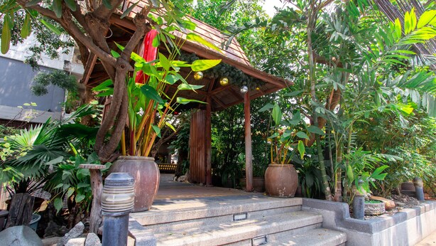 A wooden gazebo with steps leading up to it, surrounded by various potted plants and trees. - The Residence Rajtaevee Hotel (Bangkok)