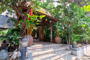 A wooden gazebo with steps leading up to it, surrounded by various potted plants and trees. - The Residence Rajtaevee Hotel (Bangkok)