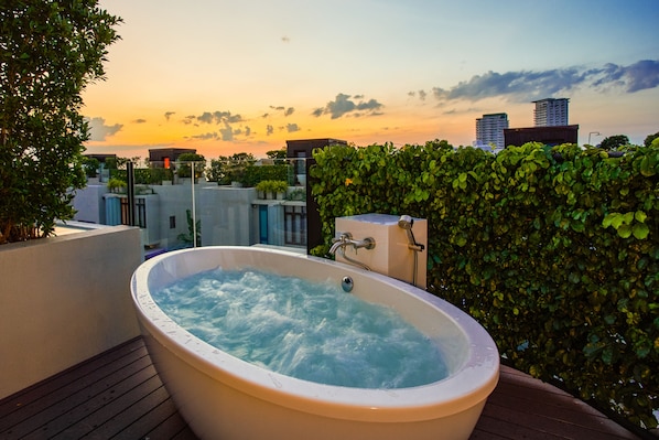 A hot tub on a rooftop with a cityscape view at sunset.