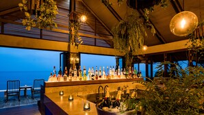 Zona de bar con vistas al mar, botellas de alcohol y un balde con hielo.