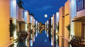 Un pasillo de hotel con un estanque reflectante, arquitectura moderna y una luna en el cielo.