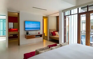Habitación de hotel moderna con una cama grande, televisión, escritorio pequeño y vista a la piscina.