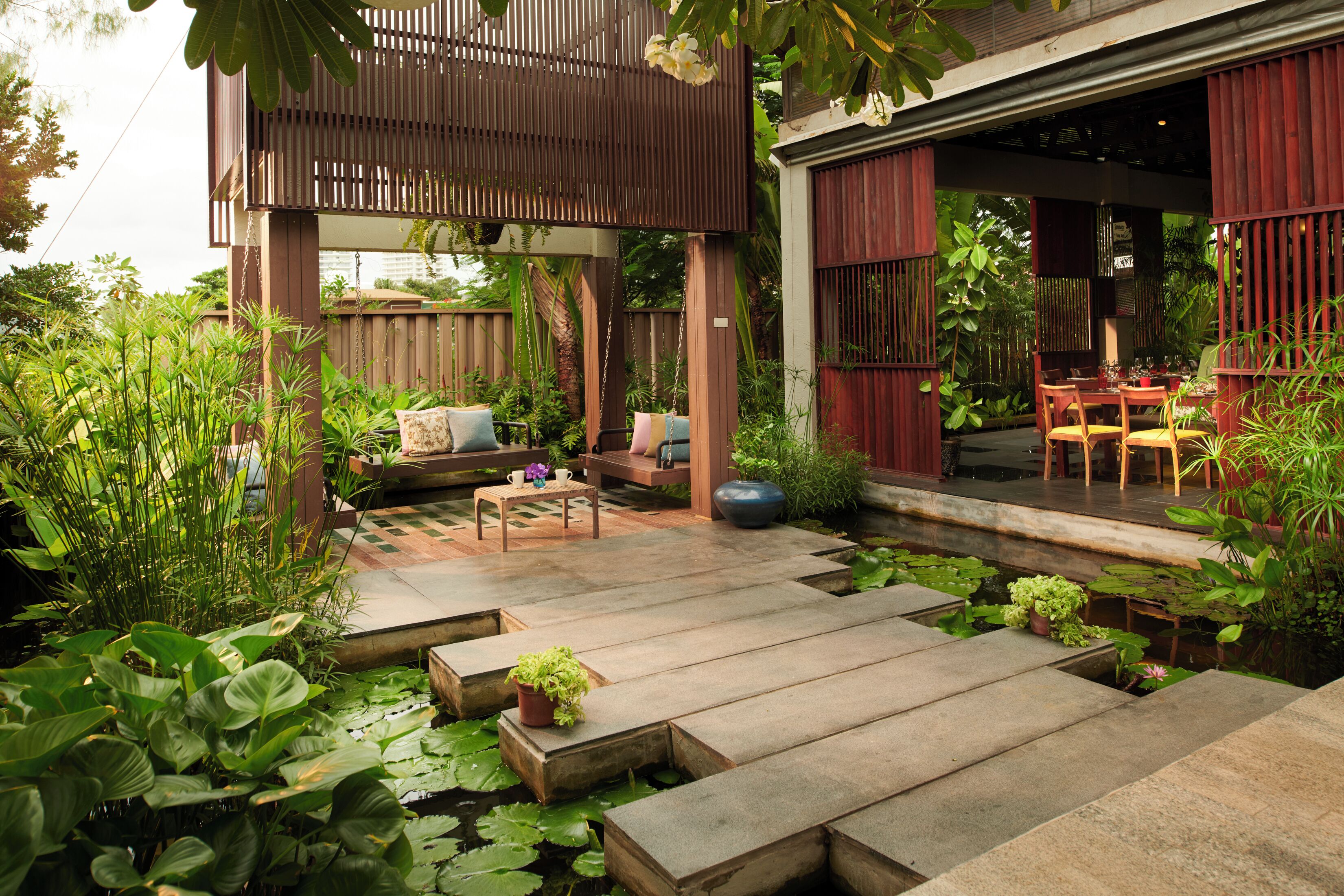 A garden patio with a wooden deck, seating area, and a dining table.