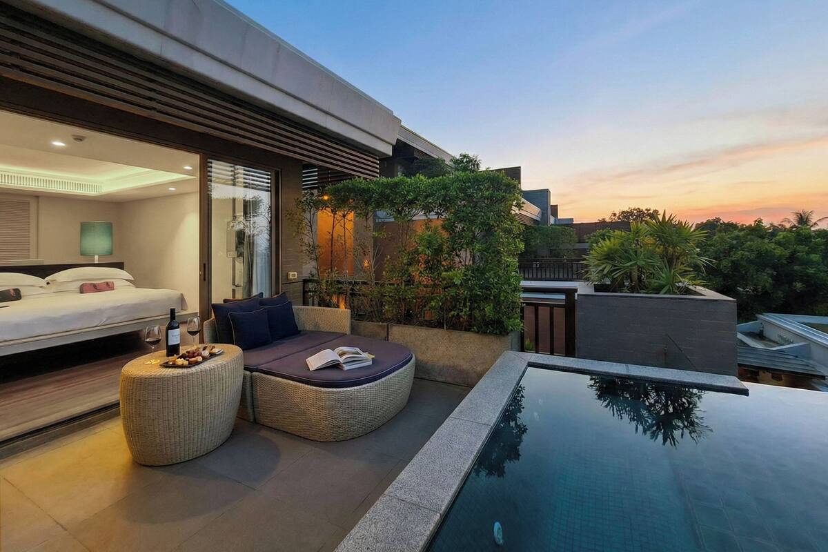 Una habitación de hotel moderna con balcón, piscina y mobiliario exterior.