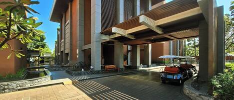 A modern building with a covered entrance, a paved courtyard, and a golf cart.