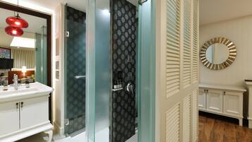 A modern bathroom with a glass shower enclosure, a white vanity with a mirror, and a round mirror on the wall.