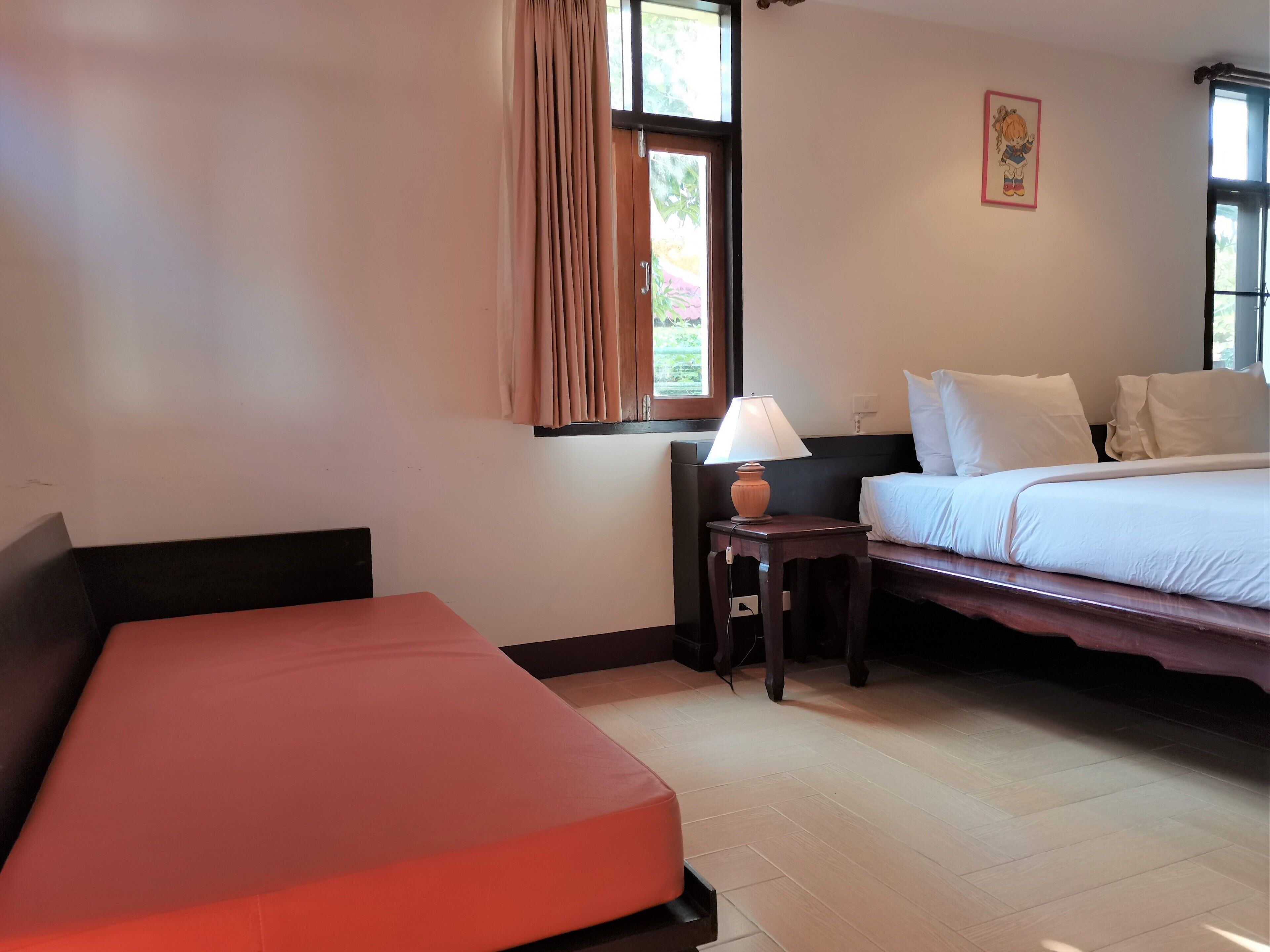 Habitación de hotel con cama, sofá, mesita de noche con lámpara y ventana con cortinas.