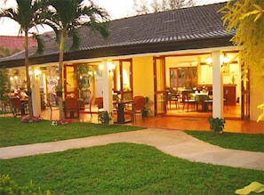 A two-story building with a tiled roof, a covered outdoor dining area, and a well-maintained lawn. - Baramie Residence (Sattahip)
