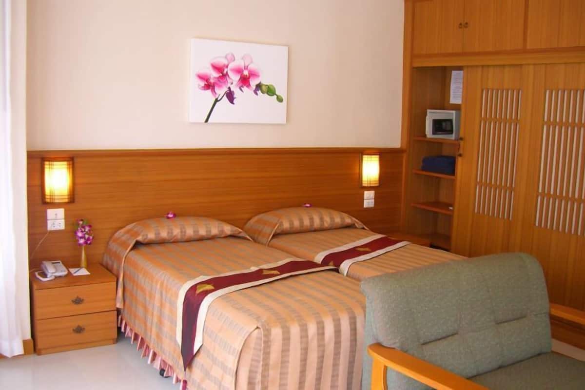 A hotel room with a double bed, bedside lamps, a desk with a telephone, a chair, and a wardrobe.