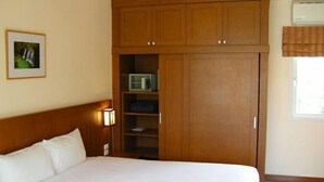 Un dormitorio con una cama, un armario de madera, estanterías y un cuadro en la pared.