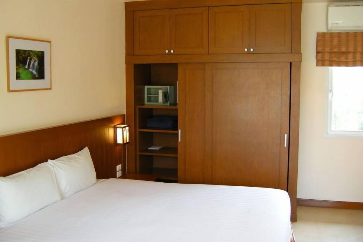 A bedroom with a bed, wooden wardrobe, shelves, and a picture on the wall.