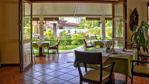 Un comedor interior con vista a un jardín y edificios.