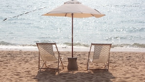 Ein Strand mit zwei Liegen und einem Sonnenschirm.