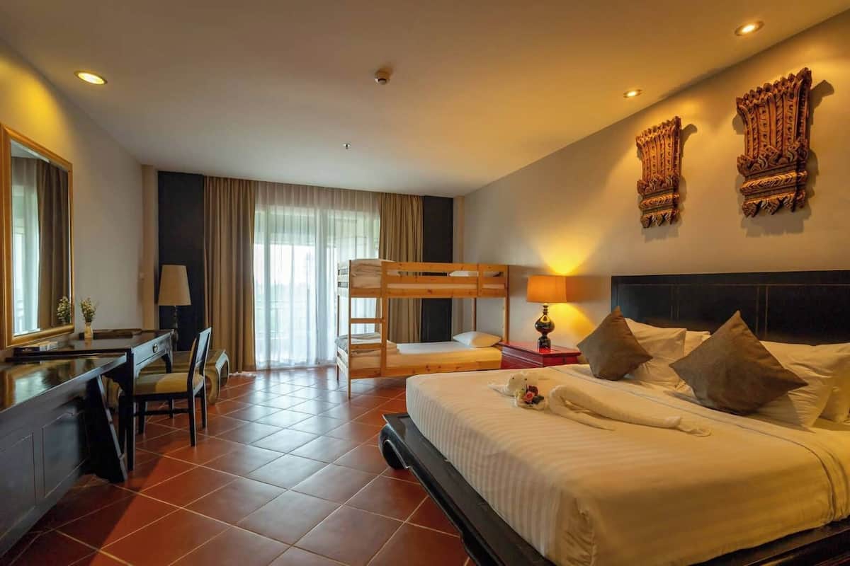 Ein Hotelzimmer mit einem Etagenbett, einem Schreibtisch mit Stuhl, einer Lampe und Wanddekoration.