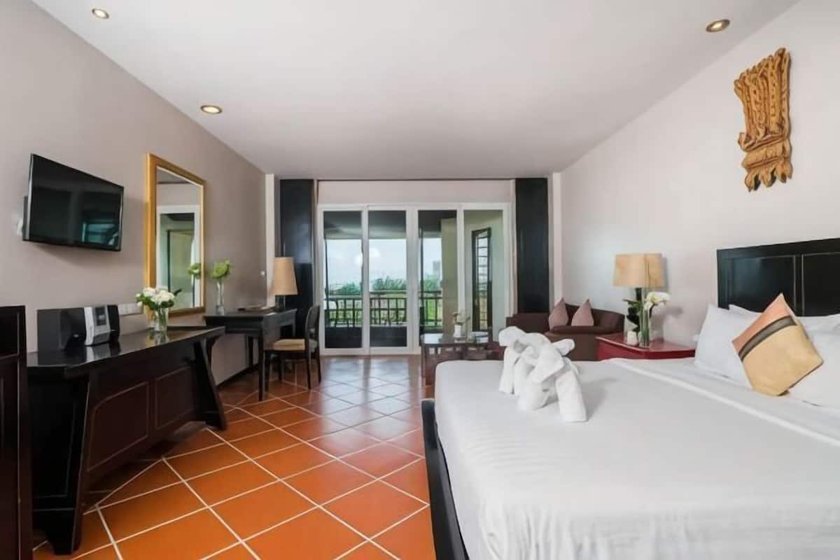 Ein Hotelzimmer mit Bett, Schreibtisch, Stuhl, Fernseher und einem Balkon mit Blick.