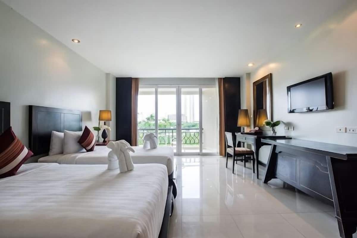 Ein Hotelzimmer mit zwei Betten, einem Schreibtisch, einem Fernseher und einem Balkon mit Blick.