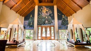Eine geräumige Lobby mit hoher Decke, einem Wandgemälde und einer großen Holztür.