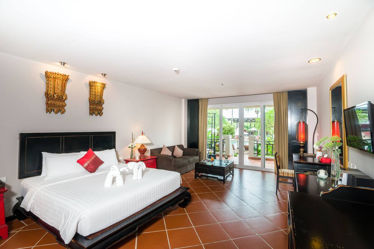 Ein Hotelzimmer mit Bett, Sofa, Schreibtisch, Fernseher und einem Balkon mit Blick.