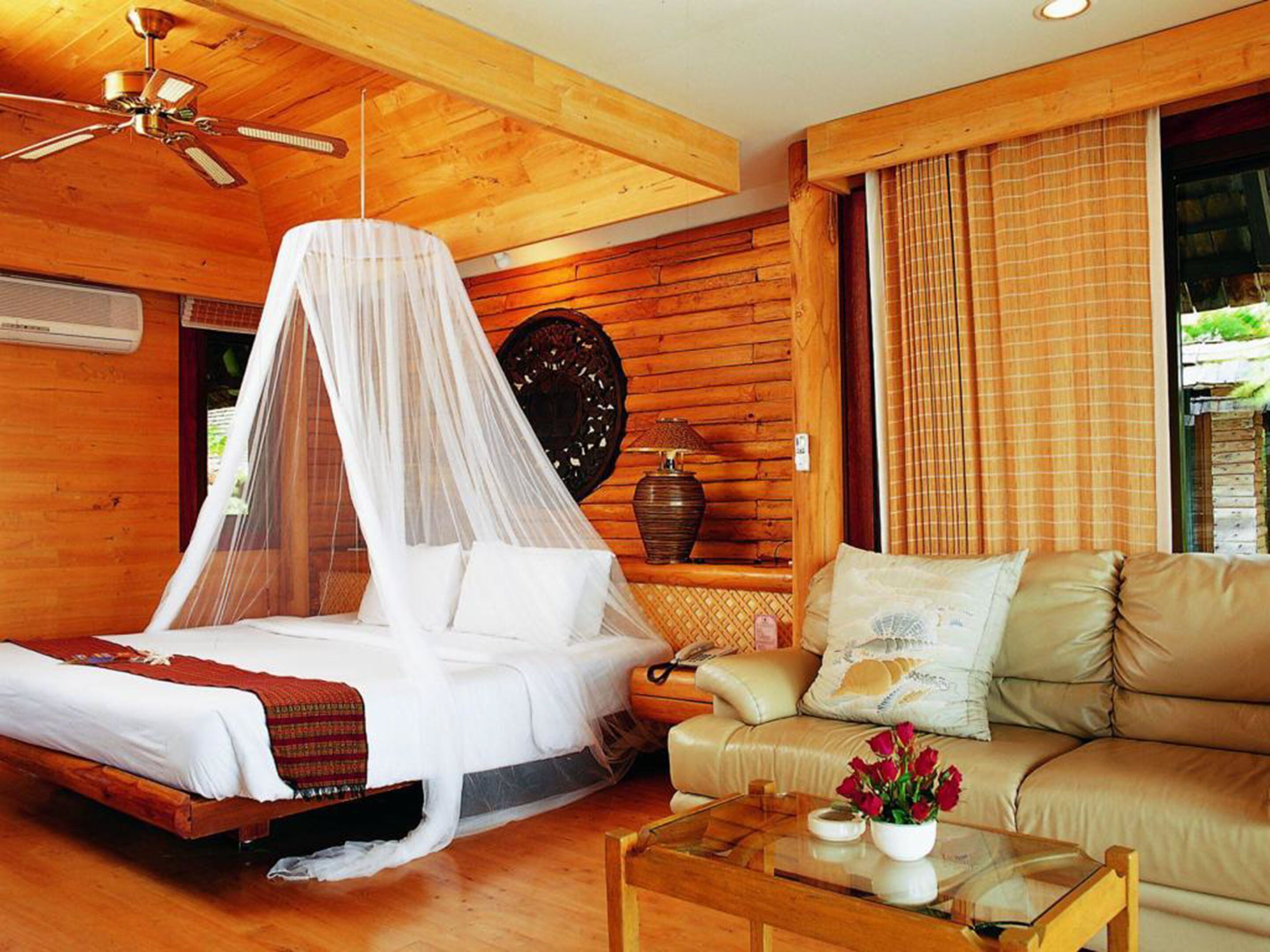 A wooden room with a bed, a sofa, and a coffee table.