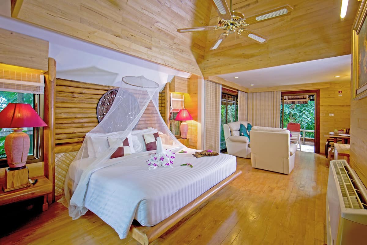 A spacious bedroom with a large bed, a sitting area, and a ceiling fan.